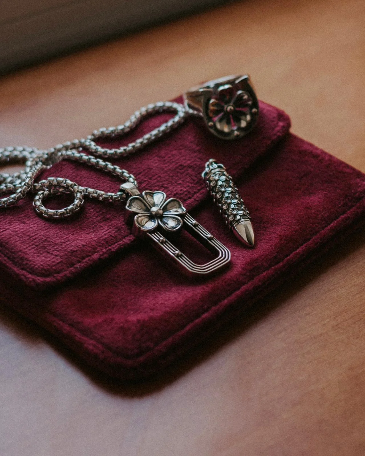 The ALLERS Ring, Arch Necklace and Bullet Necklace arranged on a burgundy jewelry box.